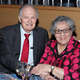 Alan Alda and Arlene Alda at a dinner table holding hands
